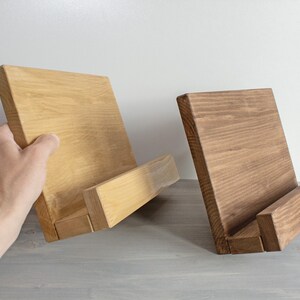 K&ouml;nnte beinhalten: Zwei Holzbuchst&uuml;tzen, eine hellbraun und eine dunkelbraun, mit einem schr&auml;gen Design, um B&uuml;cher aufrecht zu halten.