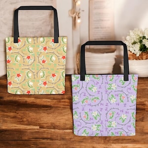 Puede incluir: Dos bolsas de mano con asas negras. Una bolsa tiene un fondo beige con un estampado floral en rojo, verde y blanco. La otra bolsa tiene un fondo morado con un estampado floral similar. Ambas bolsas tienen el texto "Do everything with love" en un círculo.
