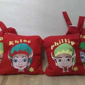 Può includere: Quattro pochette con cerniera rosse con volti di elfi ricamati e nomi: Lando, Khloe, Phillip e Jayah. Ogni pochette ha un cappello da elfo verde e una stella dorata.