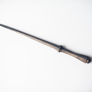 May include: A handcrafted wooden wand with a dark, weathered finish. The wand features a slender, tapered design with a detailed handle. The overall length is approximately 14 inches.