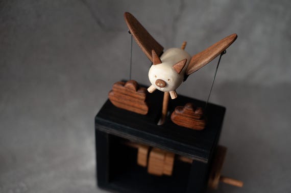A hand-carved wooden flying pig automaton that actually moves — whimsical mechanical folk art that doubles as a conversation-starting desk sculpture.