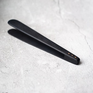May include: Black wooden tongs with gold accents. The tongs are designed for picking up food.