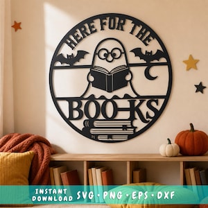 May include: A circular black wall sign featuring a ghost wearing glasses and reading an open book. The text reads "HERE FOR THE BOO-KS". Two bats and a crescent moon are integrated into the design, with a stack of books at the bottom.