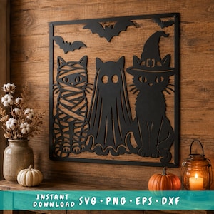 May include: A black metal wall art piece featuring a square frame with three cats in Halloween costumes: a mummy cat, a ghost cat, and a cat wearing a witch hat. Two bats are silhouetted at the top. The text reads: INSTANT DOWNLOAD SVG PNG EPS DXF.