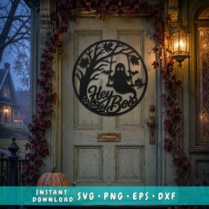 May include: A circular black metal wall sign featuring a silhouette design of a ghost on a swing under a tree, with bats and pumpkins. The text Hey Boo is written in a script font. The sign is displayed on a wooden door with autumn foliage.