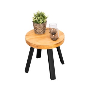 Pode incluir: Uma mesa auxiliar redonda de madeira com pernas pretas. A mesa tem uma planta em vaso e dois copos em cima.