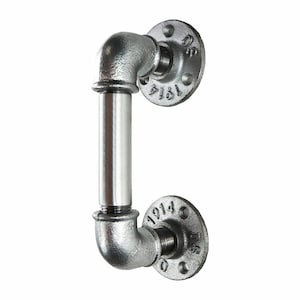 Può includere: Una maniglia per porta in metallo argentato a forma di tubo con due flange. Le flange hanno i numeri "1914" e "1914" stampati.