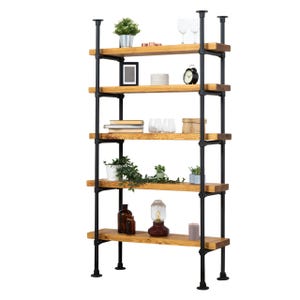 May include: A rustic, industrial-style bookshelf with five wooden shelves supported by black metal pipes. The shelves display various decorative items, including plants, books, a clock, and glassware. The overall design is a blend of natural wood and metal.