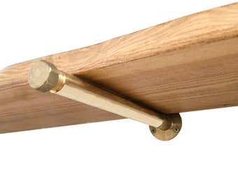 May include: A brass shelf bracket with a round base and a hexagonal cap. The bracket is attached to a wooden shelf.