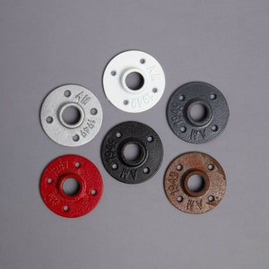 Pode incluir: Seis flanges de tubo de metal em várias cores, incluindo branco, prata, preto, vermelho e marrom. Cada flange tem um furo circular no centro e o texto "1949" e "AM" impresso no exterior.