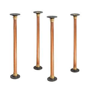 Op de afbeelding: Vier tafelpoten van koperen pijp met zwarte metalen flenzen. Elke poot is ongeveer 46 cm hoog.