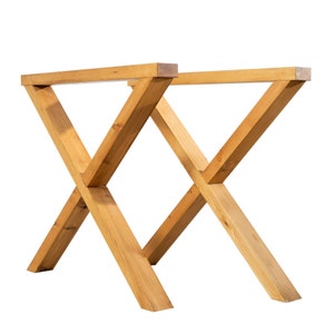 Puede incluir: Un juego de dos patas de mesa de madera en forma de cruz. Las patas son de madera natural y tienen un acabado marrón claro.