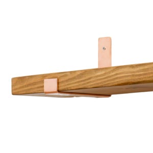 Puede incluir: Una estantería de madera con soportes metálicos de color cobre. La estantería es de madera marrón claro y tiene forma rectangular. Los soportes están montados en la parte inferior y trasera de la estantería, proporcionando soporte. La estantería está diseñada para montaje en pared.