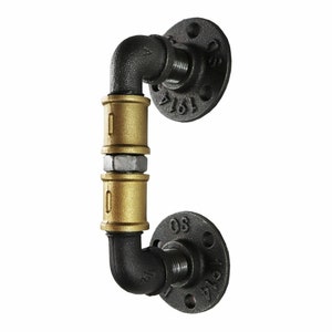 May include: Black and gold industrial style door handle made from pipe fittings. The handle has two gold coloured pipe sections with black pipe fittings and flanges.