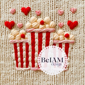 May include: A close-up of a knitted cream-colored fabric with a red and white popcorn stitch design. The design is of three popcorn containers with red and white stripes. There are small red hearts scattered around the containers. The text "BelAM design" is in a white circle with a pink background.