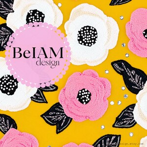 May include: A yellow fabric background with embroidered flowers in pink, white, and black. The flowers have a beaded centre. A pink circle with the text "BelAM design" is in the centre of the image.