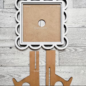 May include: A white scalloped-edge picture frame with a brown center and a circular hole. The frame is accompanied by two brown wooden stands. The text "Simply Stacey" is visible on the frame.