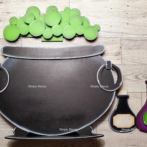 May include: A black cauldron with green bubbling potion on top, two purple potion bottles with labels that say "Spider Juice" and "Fail Tails".