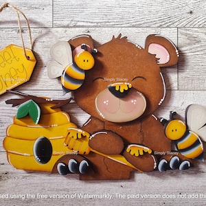 May include: Wooden cutout of a brown bear holding a honey dipper, with a bee and honeycomb behind it. The sign reads "Sweet Honey".
