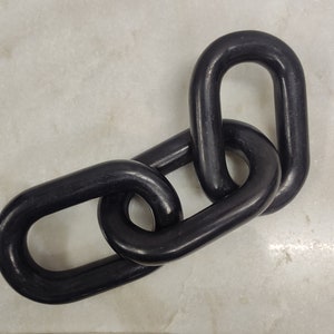 May include: Three black metal chain links connected together. The links are oval shaped and have a smooth, shiny finish.