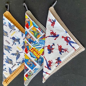 Pu&ograve; includere: Tre strofinacci da cucina triangolari con disegni di supereroi. Uno presenta Batman, un altro la Justice League e il terzo Spiderman. Ogni strofinaccio ha un bordo a nido d'ape e un anello per appenderlo.