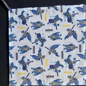 Pu&ograve; includere: Tessuto quadrato e chiaro con un motivo ripetuto di personaggi di Batman in varie pose. La parola "BATMAN" &egrave; stampata in giallo. Il tessuto ha un passante a pois bianchi e neri.