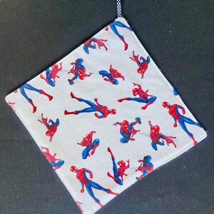 Pu&ograve; includere: Tessuto quadrato bianco con un motivo ripetuto di figure di Spider-Man rosse e blu. Un anello a pois bianchi e neri &egrave; attaccato a un angolo. I bordi sono rifiniti con una cucitura rossa.