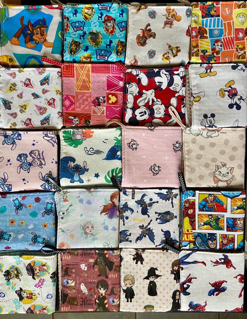 Pu&ograve; includere: Una collezione di piccole pochette quadrate in tessuto con varie stampe di personaggi dei cartoni animati, tra cui Paw Patrol, Topolino e supereroi. Ogni pochette ha un anello per appenderla e presenta un motivo e una combinazione di colori unici.