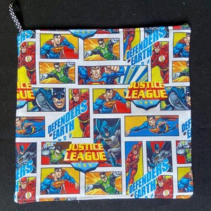 Pu&ograve; includere: Presina quadrata trapuntata con un design a fumetti con Superman, Batman e Flash. Sono visibili anche le parole "Justice League" e "Defenders of Earth". Ha un anello a pois bianchi e neri per appenderla.