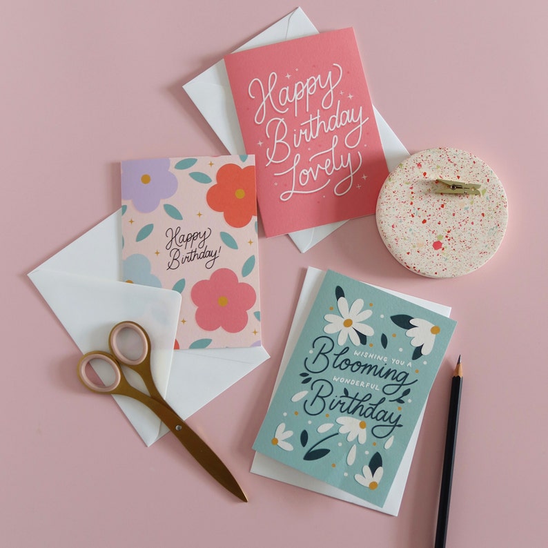 Image of three happy birthday cards. Flowery card with the text 'wishing you a blooming wonderful birthday' hand lettered.