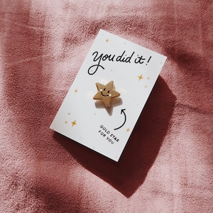 A white card with the text "You did it!" and a gold star with a smiley face. The card also says "Gold Star for You".