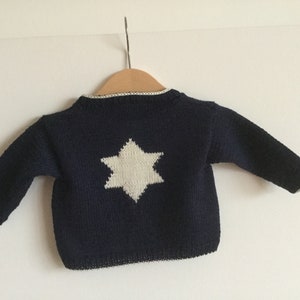 Puede incluir: Un suéter de punto azul marino con un diseño de estrella blanca en la espalda.