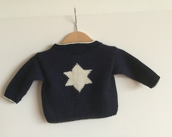 May include: A navy blue knitted sweater with a white star design on the back.