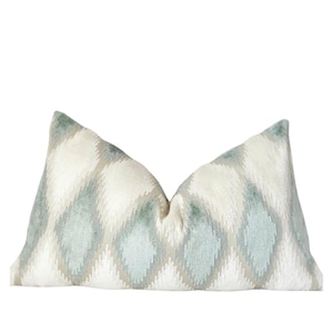 May include: A decorative throw pillow with a white background and a geometric pattern in shades of blue and gray.