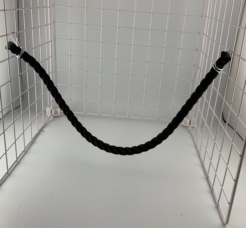 Black rope pet toy suitable to hang in cage. The rope is in a curved shape and is attached to the cage with metal hooks.