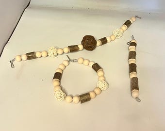 Op de afbeelding: Drie houten kralenkransen met witte en bruine kralen. De kransen zijn geregen op zilverdraad en hebben aan elk uiteinde een klein metalen haakje. De middelste krans heeft een grote, ronde, geweven bal in het midden.