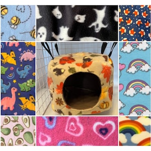 Puede incluir: Una colección de muestras de tela con varios patrones, incluyendo dinosaurios, fantasmas, estrellas, arcoíris, aguacates y corazones. Las muestras están dispuestas en una cuadrícula, con una pequeña cama colgante para mascotas en el centro.