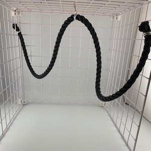 Black rope pet toy suitable to hang in cage. The rope is in a curved shape and is attached to the cage with metal hooks.