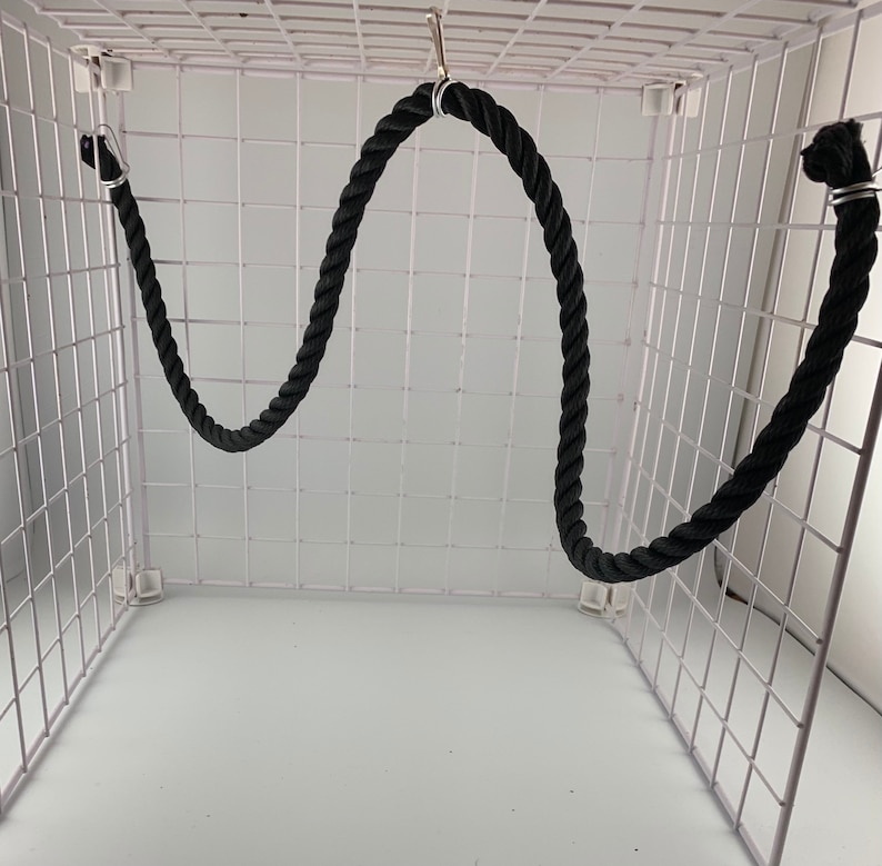 Black rope pet toy suitable to hang in cage. The rope is in a curved shape and is attached to the cage with metal hooks.