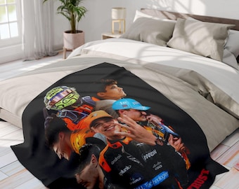 May include: Black and white throw blanket with a group of people wearing racing helmets and racing suits. The blanket has the text "Ando We Trust" printed on it.