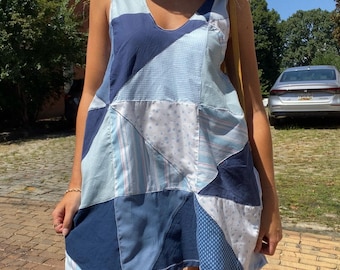 May include: A sleeveless patchwork dress in shades of blue, featuring a V-neckline. The dress is composed of various fabric patterns, including gingham, stripes, and polka dots. The dress is knee-length and appears to be handmade.