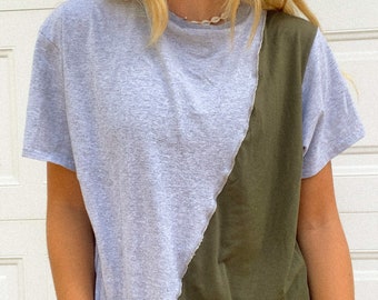 May include: A gray and olive green t-shirt with a diagonal seam. The shirt has a relaxed fit and short sleeves.