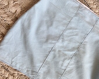 May include: A light blue gingham skirt with a white gingham pattern. The skirt is made of a soft, lightweight fabric and has a straight, A-line silhouette.