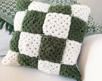 May include: A green and white checkered crochet pillow. The pillow is made of soft yarn and has a square shape.