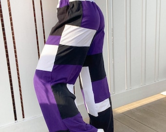 May include: Purple, black, and white checkered pants with a wide leg silhouette. The pants have a white elastic waistband.