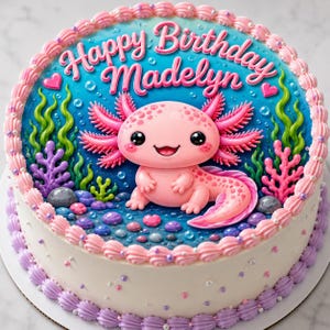 May include: A round birthday cake with a blue and white base, decorated with a pink axolotl and the words "Happy Birthday Madelyn". The cake features pink and purple frosting accents, seaweed, and bubble details.