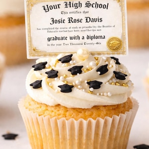 May include: A graduation cupcake with white frosting, decorated with black graduation caps, gold sprinkles, and white pearl sprinkles. A diploma-shaped card is inserted into the cupcake, with the text "Your High School" and "graduate with a diploma".