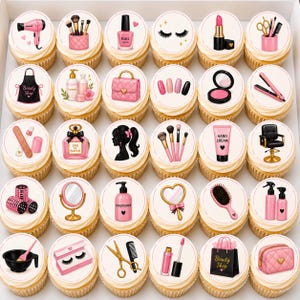 May include: A collection of cupcakes with various beauty-themed designs. Each cupcake features a white frosting circle with images of makeup, hair styling tools, and beauty products. Designs include a hairdryer, nail polish, lipstick, and a beauty shop bag.