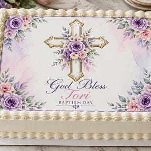 May include: A rectangular cake with white frosting and a decorative top. The top features a gold cross adorned with purple and pink flowers, surrounded by floral arrangements. The text "God Bless Tori Baptism Day" is also displayed.