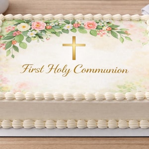 May include: A rectangular cake decorated with white frosting and a floral design. The cake features a gold cross and the words "First Holy Communion" in gold script. The floral design includes pink roses and green leaves.